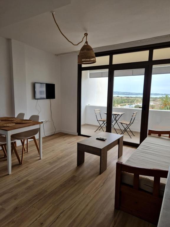 a living room with a table and a view of the ocean at Mirada Ponent in Es Pujols