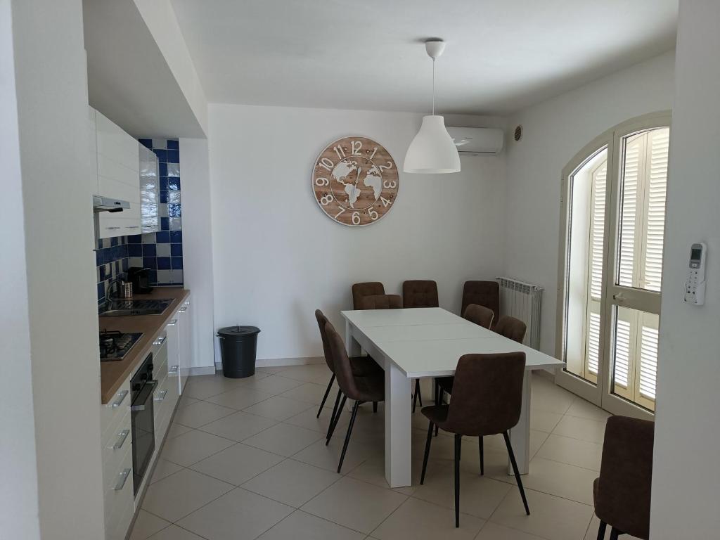 ポルト・サント・ステーファノにあるLuxury beach houseの白いテーブルと椅子のあるキッチンとダイニングルーム