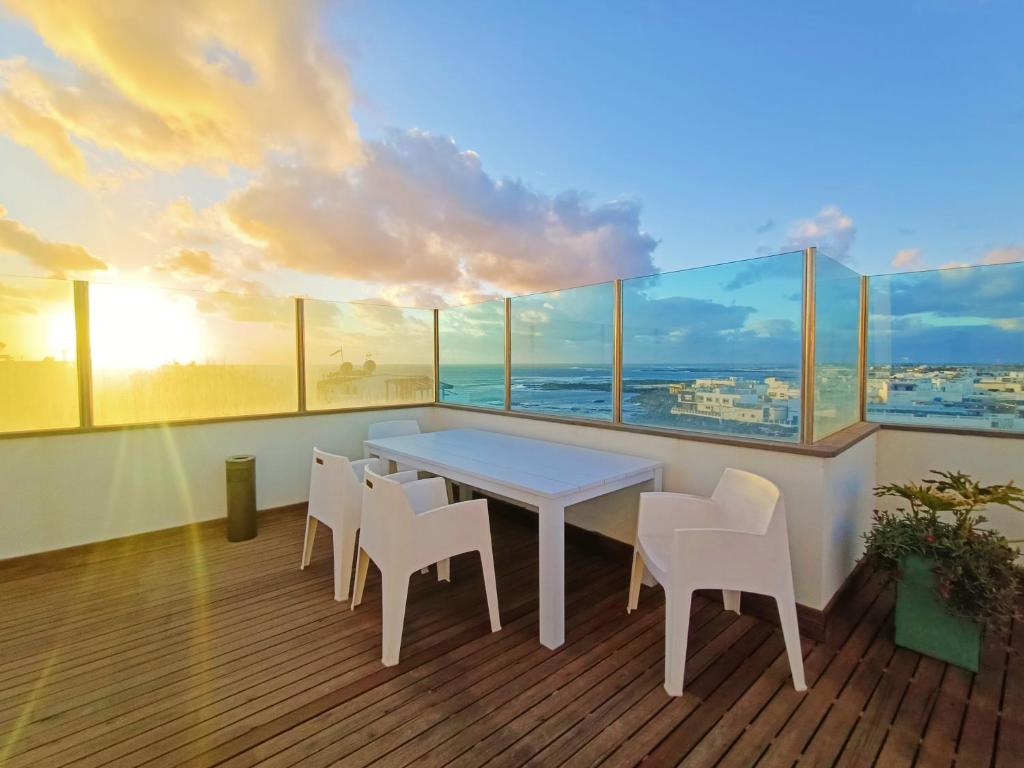 un tavolo bianco con sedie in una stanza con finestre di Sun&Sand Cotillo a Cotillo