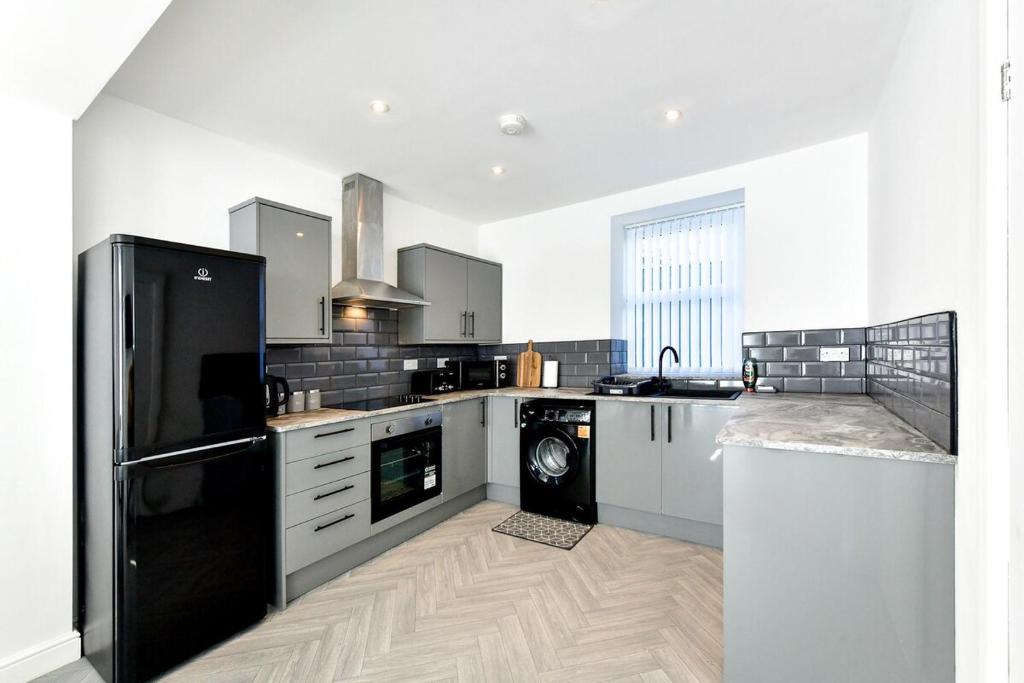a kitchen with a black refrigerator and a dishwasher at Local City Centre 3 Bedroom House in Clydach