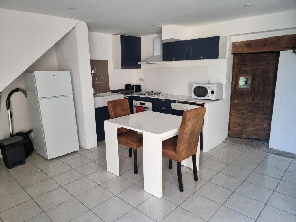 une petite cuisine avec une table et des chaises blanches dans l'établissement L'apaisant, à Rodez
