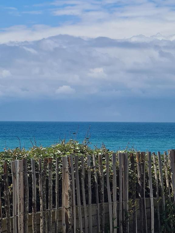 une clôture en bois avec l'océan en arrière-plan dans l'établissement Appartement a 50m de la plage, à Biscarrosse