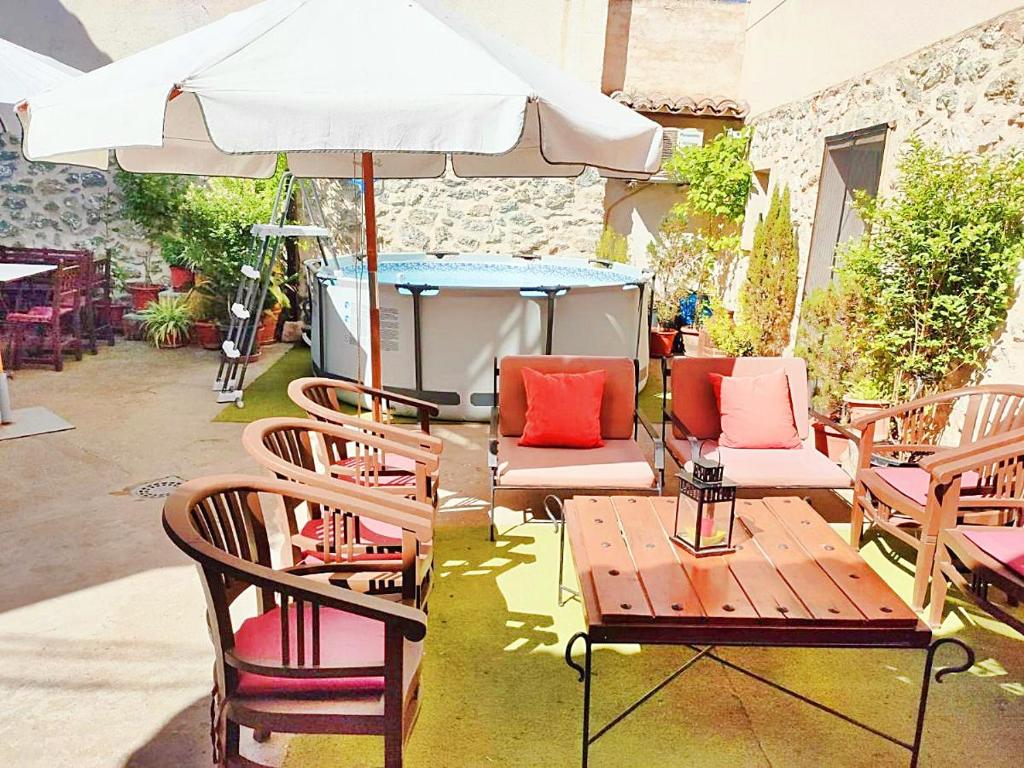 a patio with chairs and a table with an umbrella at Casa Rural El Cencerro in Villamanrique de Tajo