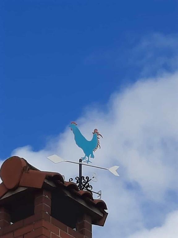 a weather vane with a chicken on top of a building at El Gallo Azul in Oruña