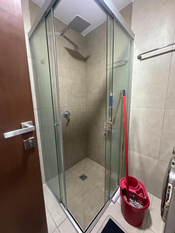 a glass shower with a red bucket in a bathroom at Cuarto privado in Santa Cruz de la Sierra