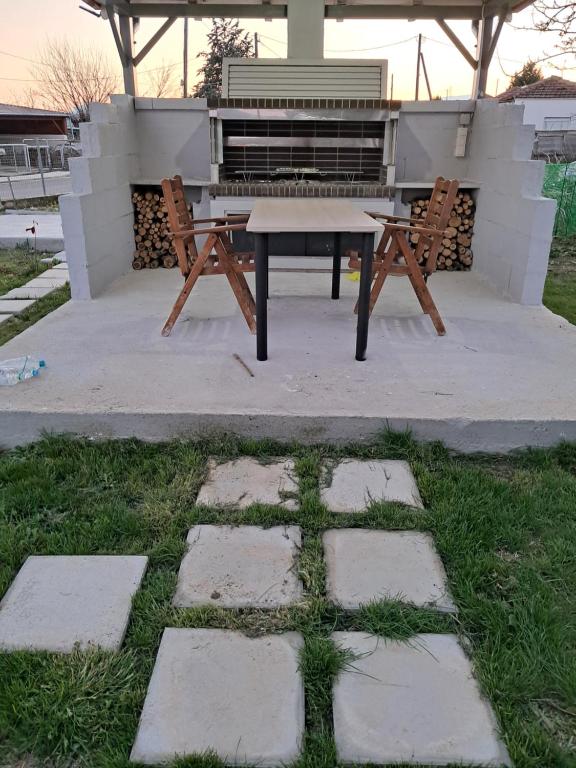 a picnic table and benches in front of a grill at Cozy Bungalow in Tríkala