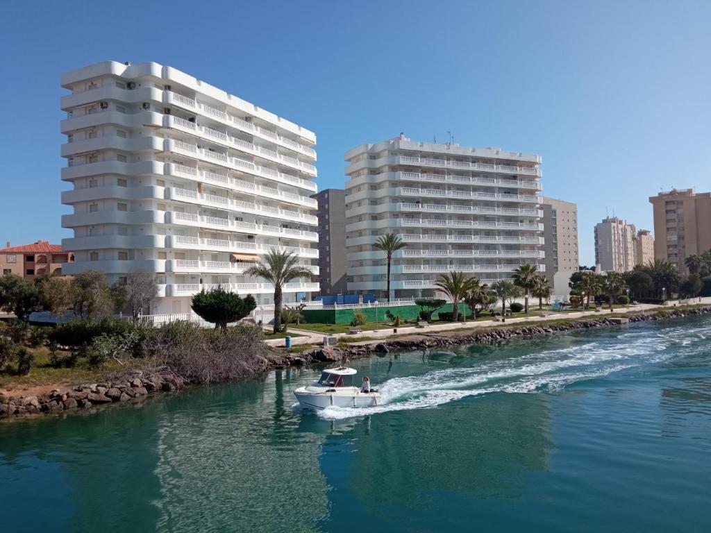 un bateau dans une rivière dans une ville avec des bâtiments dans l'établissement VENECIA AZUL, sunny terrace & beautiful sea views, à La Manga del Mar Meno