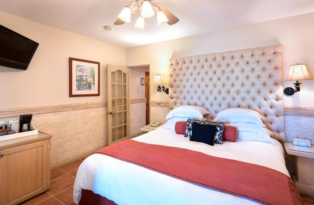 a bedroom with a large bed and a television at Little Arches Boutique Hotel - Adults Only in Christ Church