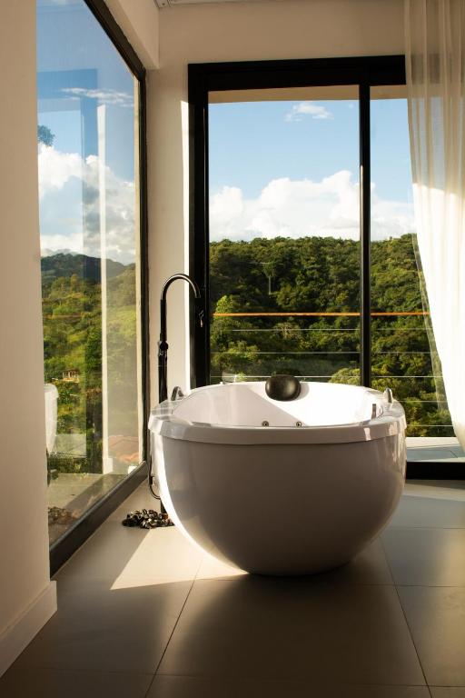a bath tub in a room with a large window at Chalé Monte Lumier in Tiradentes