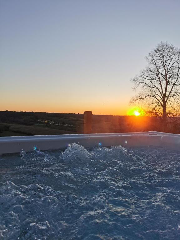 un bassin d'eau avec le coucher du soleil en arrière-plan dans l'établissement Le chalet de fayolle, à Montrem