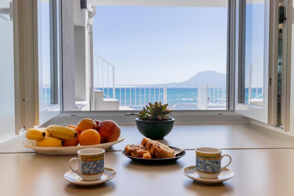 a table with two cups of coffee and a bowl of fruit at Cozy SeaView apartment in Paralía Kímis