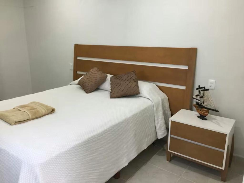 a bedroom with a white bed and a night stand at Departamento A Fracc Cd Del Valle in Tepic
