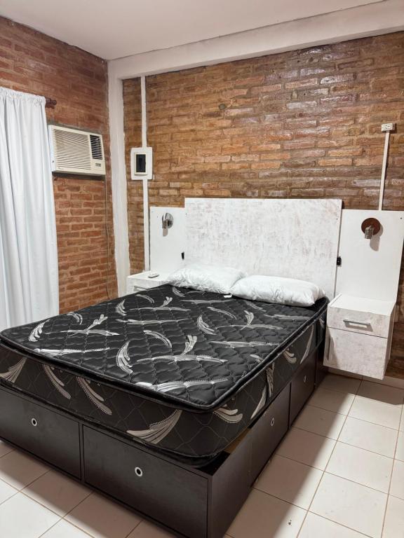 ein großes Bett in einem Zimmer mit Ziegelwand in der Unterkunft Casa en Paso de la Patria in San Cosme