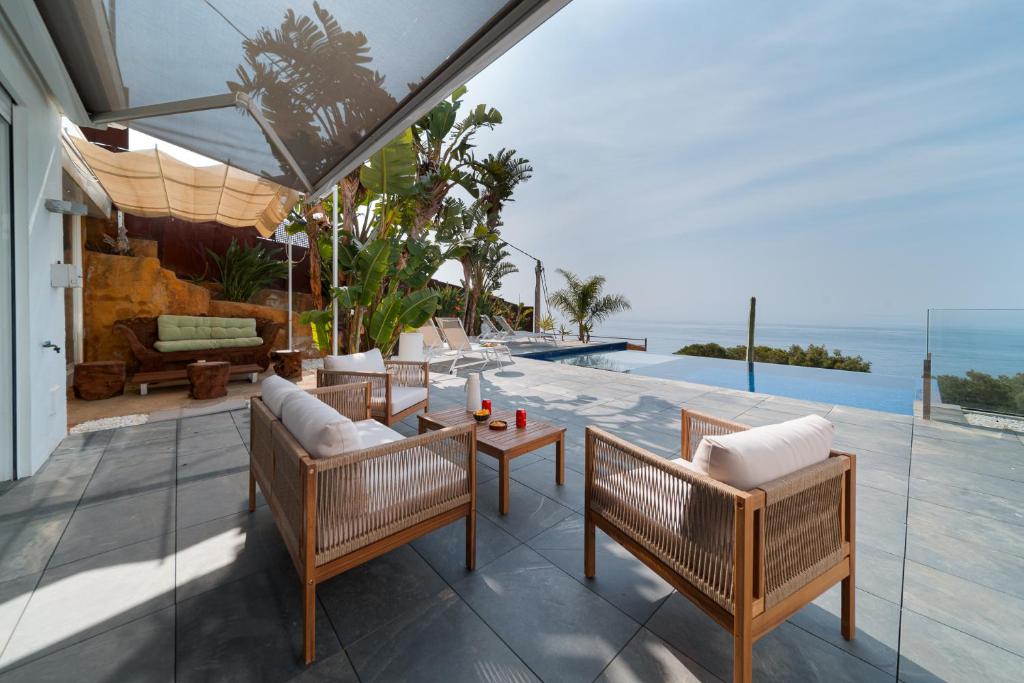 eine Terrasse mit Stühlen, einem Tisch und einem Pool in der Unterkunft Vista Roses Mar - Cases del Far in Roses