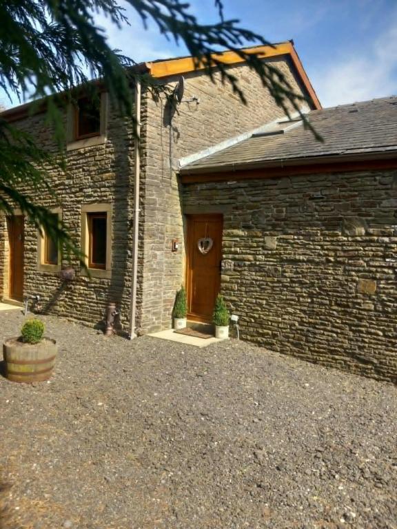 a brick house with a brown door and a yard at Walls Clough in Rossendale