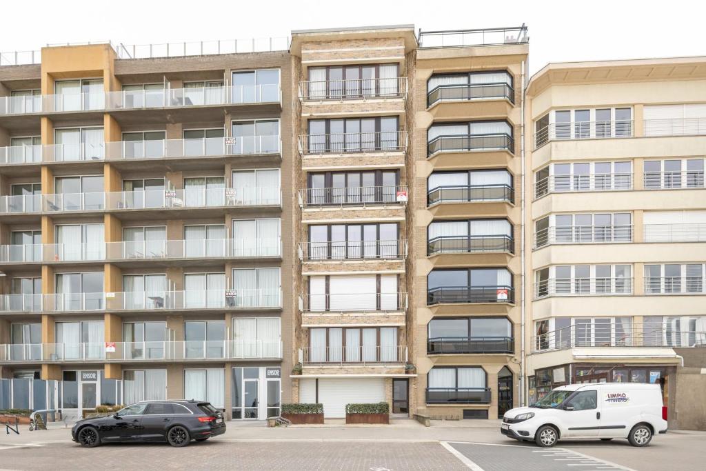 zwei Autos auf einem Parkplatz vor einem Gebäude geparkt in der Unterkunft Jackylène 0401 in Koksijde