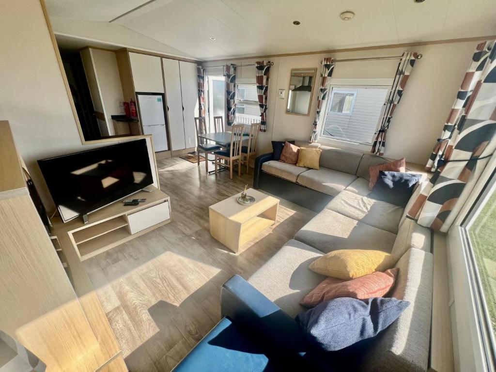 a living room with a couch and a tv at Reevas Retreat at Littlesea Holiday Park, Weymouth in Wyke Regis