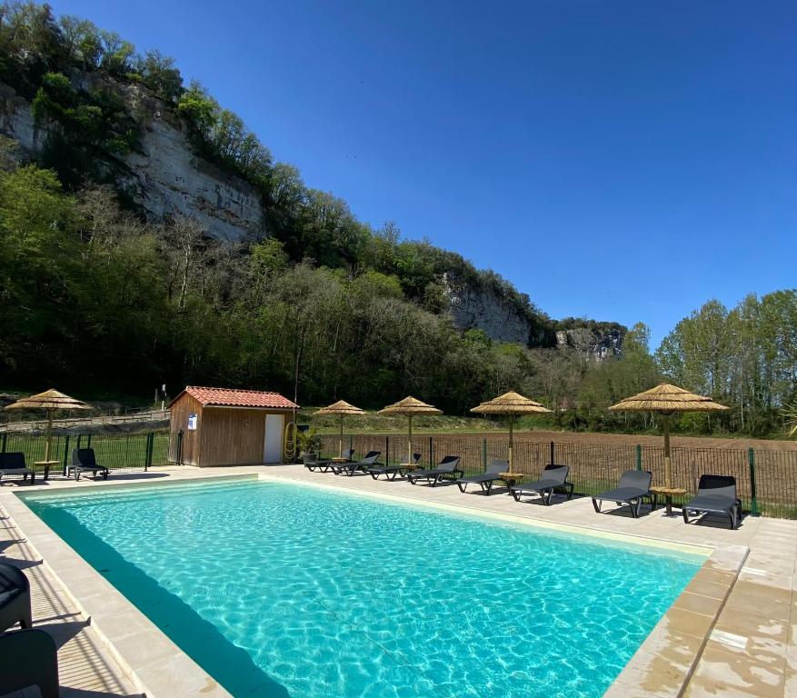 une piscine avec chaises et parasols dans l'établissement Camping LE MOULIN DE CAUDON, à Domme