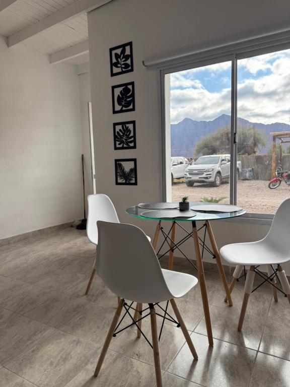 Un comedor con una mesa de cristal y sillas blancas. en Complejo Laguna Brava, en Vinchina