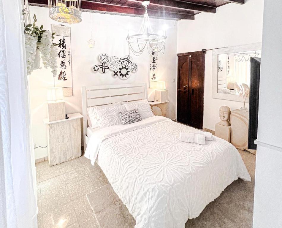 a white bedroom with a bed and a chandelier at ORHO HOTEL BOUTIQUE PANAMA Tocumen Airport free shuttle highway round trip 15 minuts in Tocumen