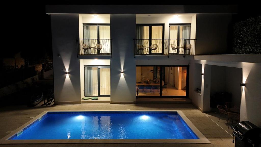 una casa con piscina di fronte a un edificio di White Villa, Brac a Splitska