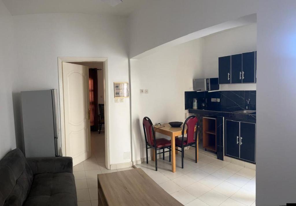 a living room with a table and chairs and a kitchen at Les résidences Astou et Ndiaga in Dakar