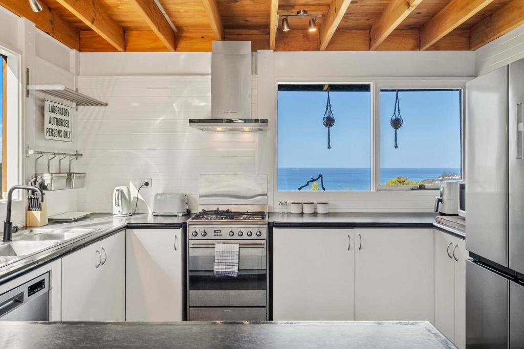 a kitchen with white cabinets and a view of the ocean at Ocean Views 20kms from CBD Sleeps 10 in Kingston Beach