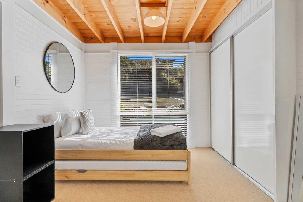 a white bedroom with a bed and a window at Ocean Views 20kms from CBD Sleeps 10 in Kingston Beach