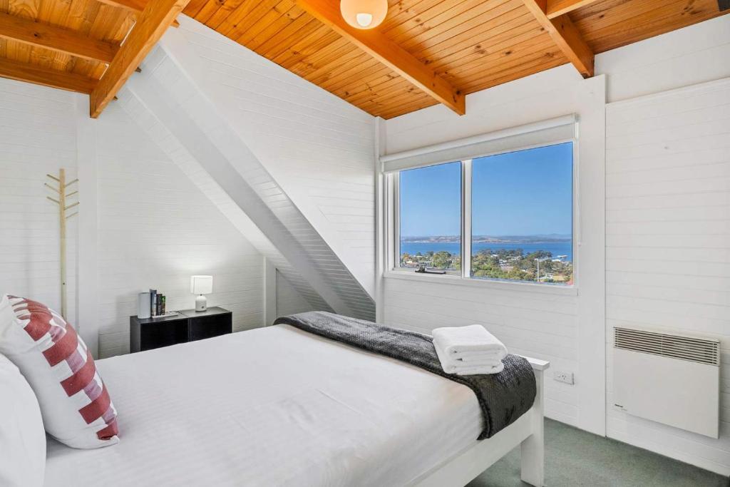 a bedroom with a white bed and a large window at Ocean Views 20kms from CBD Sleeps 10 in Kingston Beach