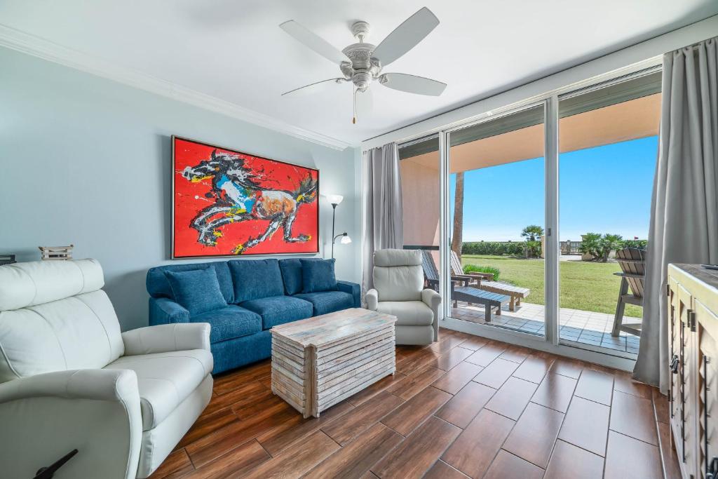 a living room with a blue couch and a chair at Doral 103 - Charming Beachfront / Ground Floor Condo! in Gulf Shores