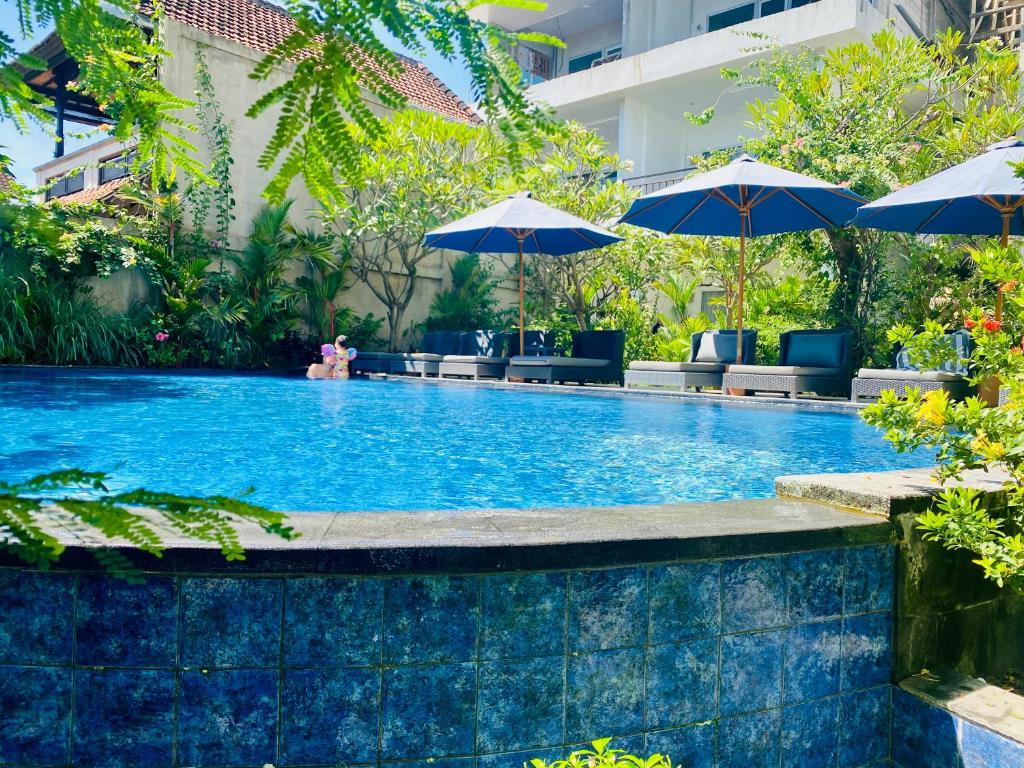 a large swimming pool with umbrellas and chairs at Solaluna Beach Homestay in Amed