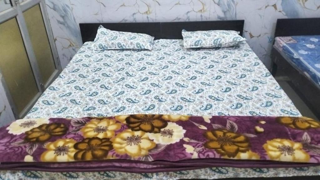 a bed with a floral comforter on it at श्री कृष्णा होम स्टे in Vrindāvan
