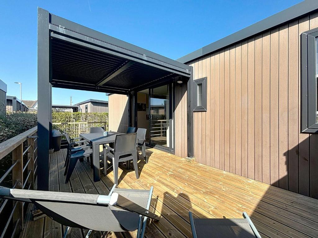 un patio avec une table et des chaises sur une terrasse dans l'établissement Mobil-home confort 6 pers, 3 ch, pisc chauffée, à 200m plage Jullouville - FR-1-361A-70, à Jullouville