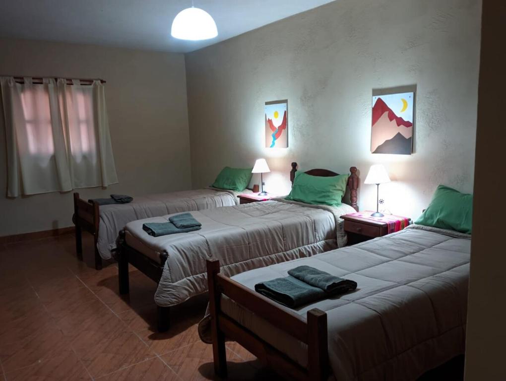 a room with three beds with green pillows at Casa Lago in La Silleta