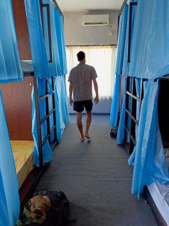 Ein Mann geht einen Flur entlang in einem Zimmer mit Etagenbetten in der Unterkunft Local Hostel Amed in Amed