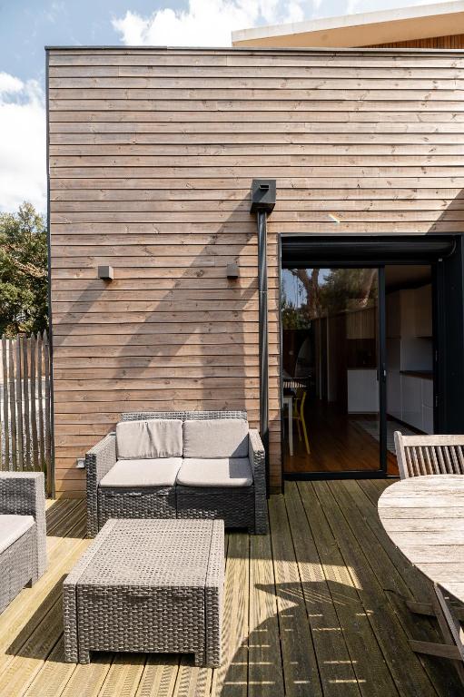 un patio avec un canapé et des tables sur une terrasse en bois dans l'établissement Villa Cocoon Contis océan à 900m, à Lit-et-Mixe