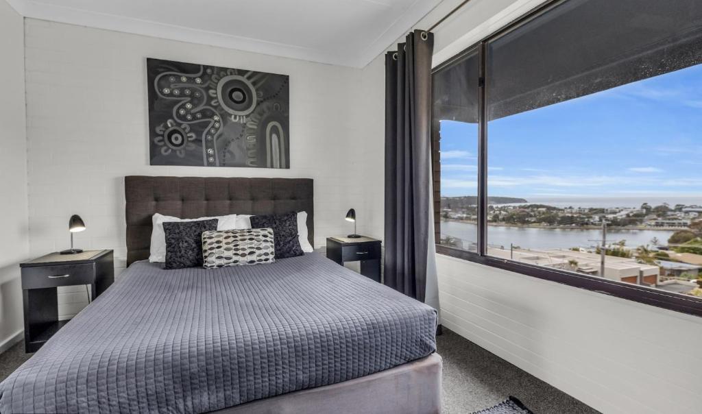 a bedroom with a bed and a large window at 2 Bedroom - 2 level apartment - Hydra Holiday Unit 2, Merimbula in Merimbula