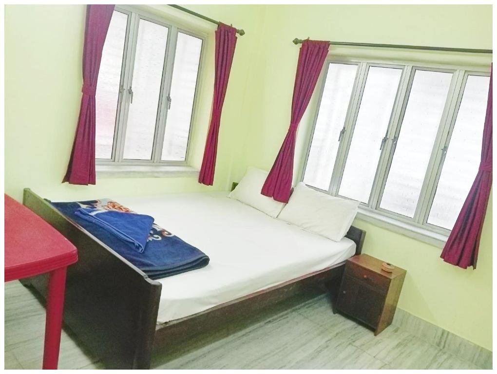 a small bed in a room with two windows at HOTEL PREMIUM PUJA Near Mandirpara JHEEL in Jādabpur