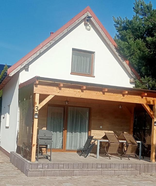 a house with chairs and a table in front of it at Domki u Eweli CAŁOROCZNE ogrzewane kominkiem in Stegna