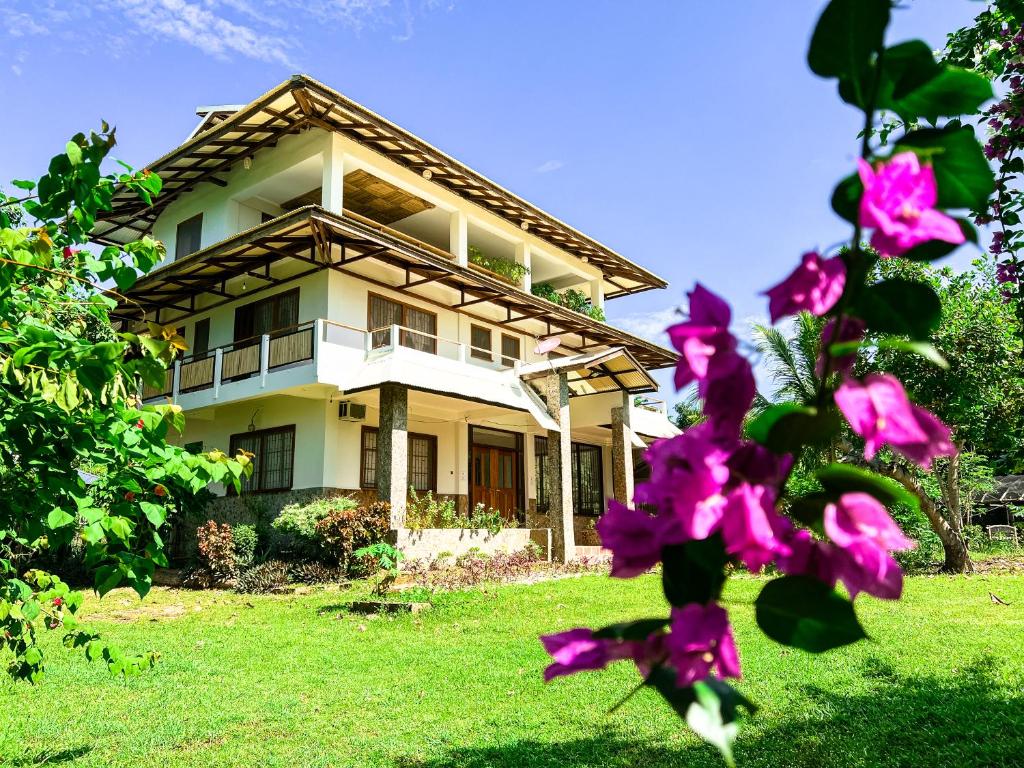 a house with pink flowers in front of it at Sandybridge Eco Farm at Relly's Restaurant in Puerto Princesa City