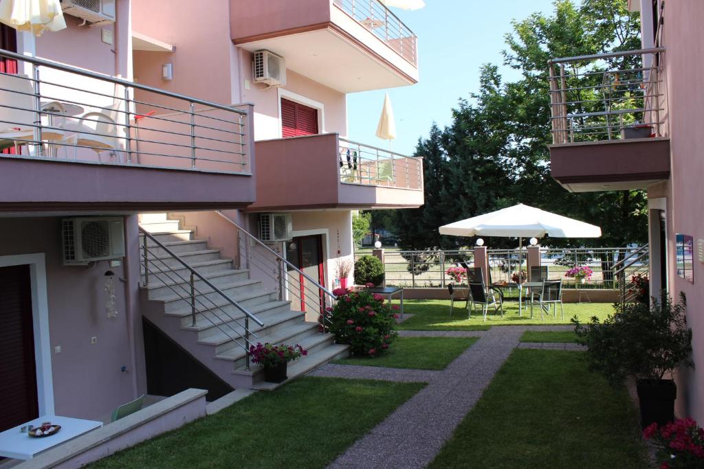 an apartment building with stairs and a yard with a patio at Yasoo Holiday Apartments in Olympiada