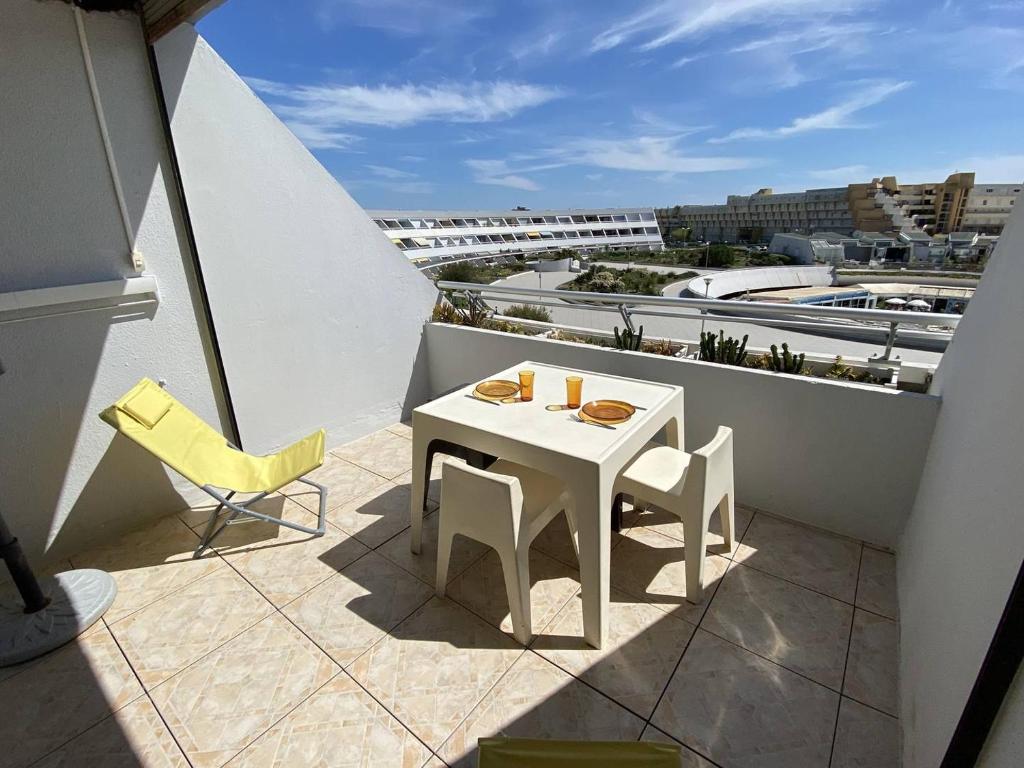 une table blanche et des chaises sur un balcon avec vue dans l'établissement Appartement 4 couchages CAP D'AGDE NATURISME CN030-309, au Cap d'Agde