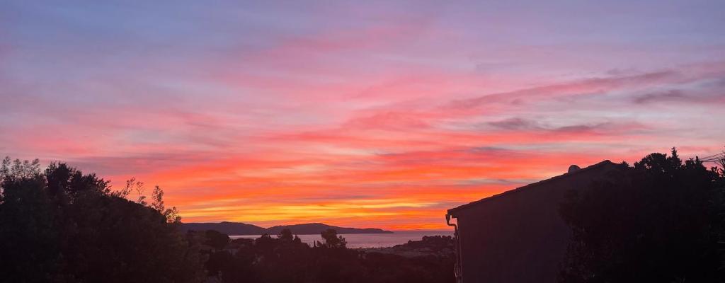 un coucher de soleil avec un bâtiment au premier plan dans l'établissement Vue mer et chant des oiseaux, à Cavalaire-sur-Mer