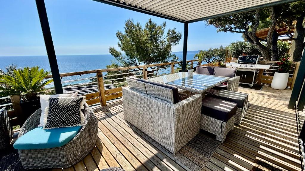 una terraza con mesa, sillas y el océano en BUNGALOW DOMAINE DE L'ILE D'OR, en Saint-Raphaël