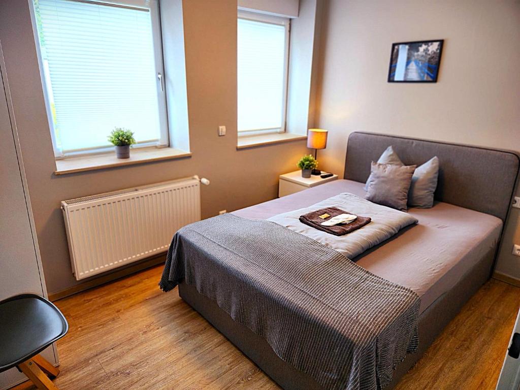 a bed in a bedroom with two windows at Stadt Apartments Solingen in Solingen
