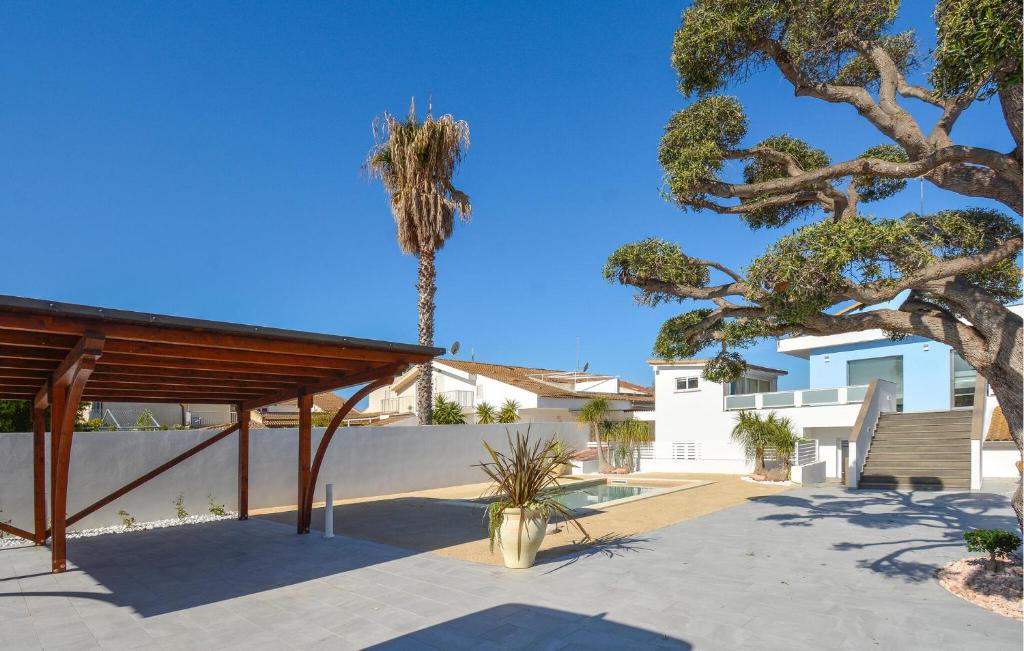 eine Palme vor einer weißen Wand mit einem Gebäude in der Unterkunft 4 Bedroom Amazing Home In Kaukana in Villaggio Azzurro