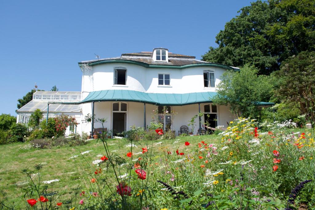 una gran casa blanca con un campo de flores en Woodlands, Teignmouth, en Teignmouth
