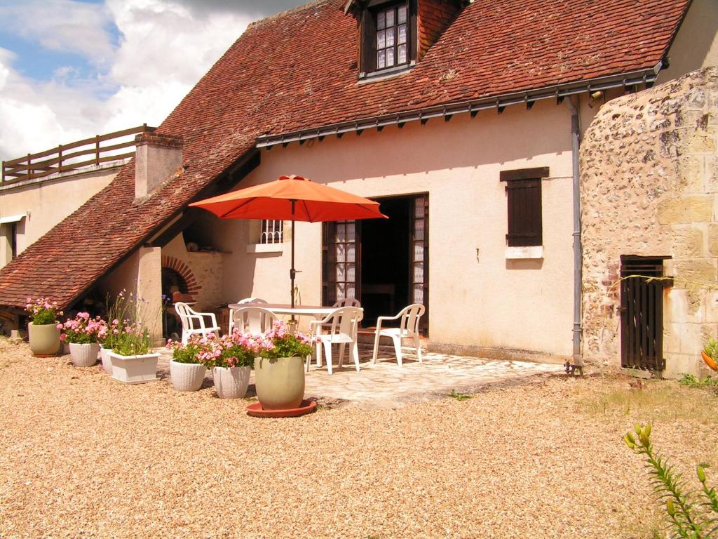 une terrasse avec une table et un parasol en face d'une maison dans l'établissement chez MAJOS un HAVRE DE PAIX, à La Celle-sous-Gouzon