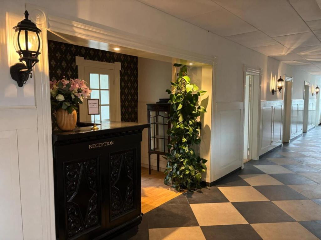 un corridoio con pavimento a scacchi e piante in un edificio di Vrensted Hostel B&B a Løkken