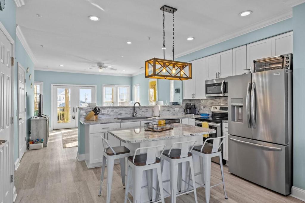 アトランティックビーチにあるAtlantic Blue townhouseのキッチン(冷蔵庫、テーブル、バースツール付)
